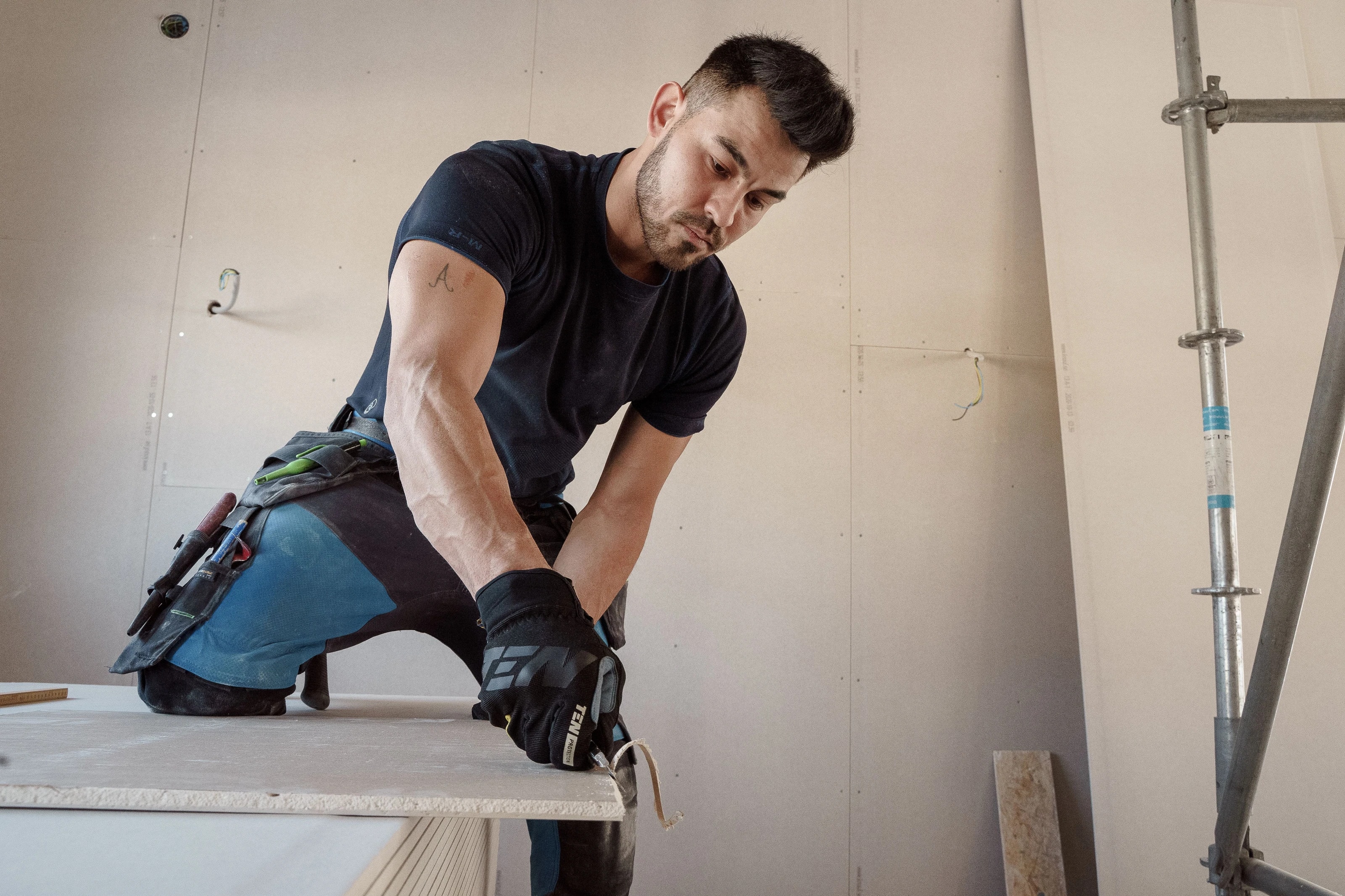 Un artisan découpe un panneau de plâtre sur un chantier de rénovation