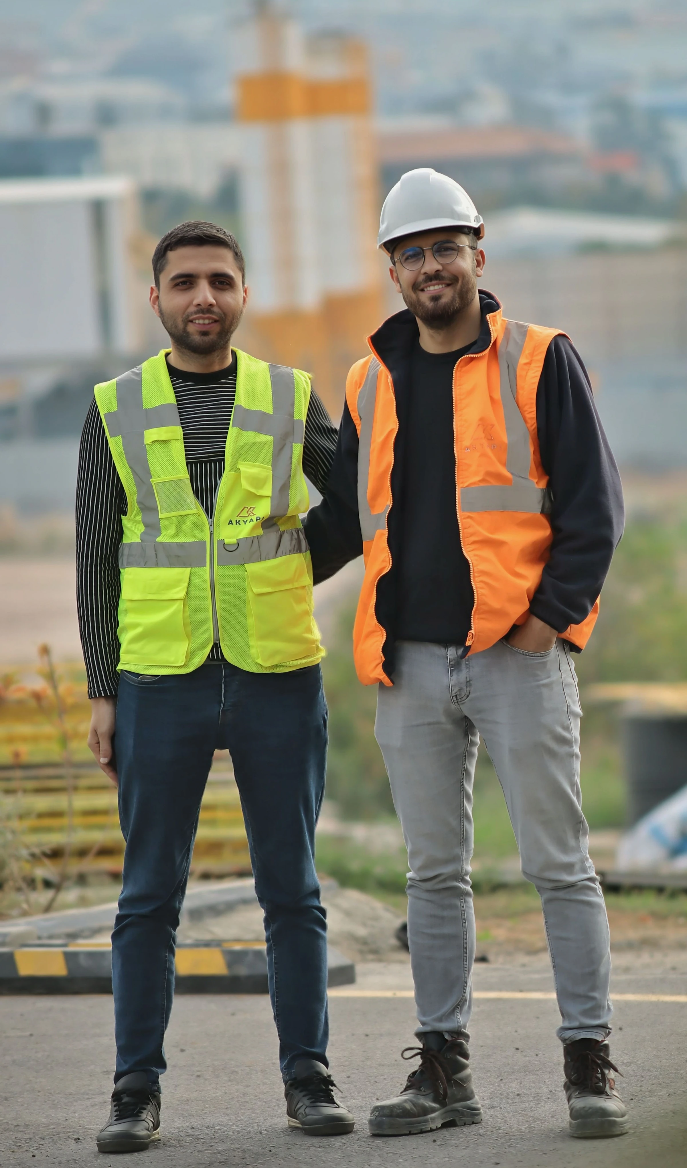 Deux artisans en gilet de sécurité posent côte à côte sur un chantier